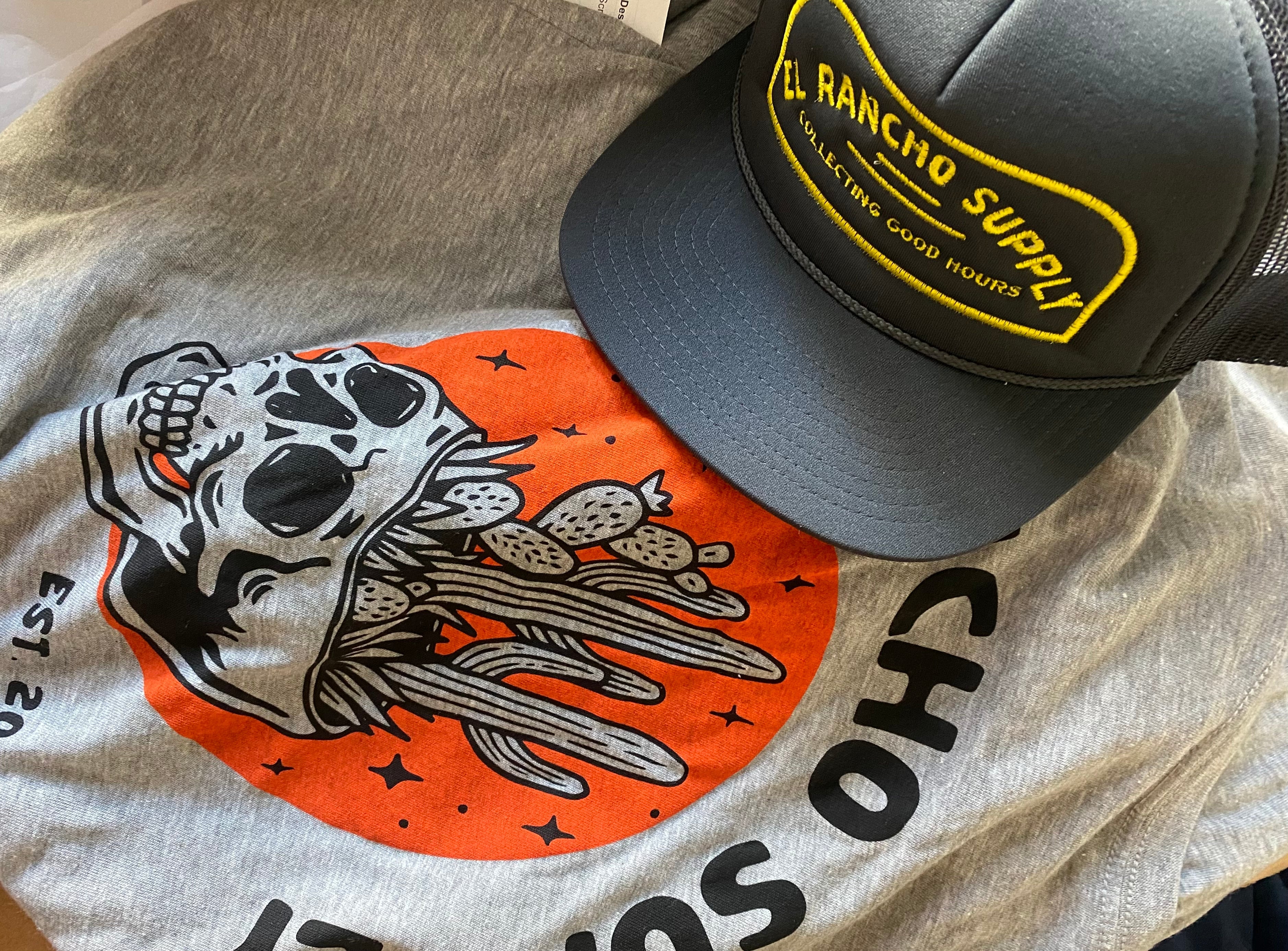 Black trucker hat laying on grey tshirt