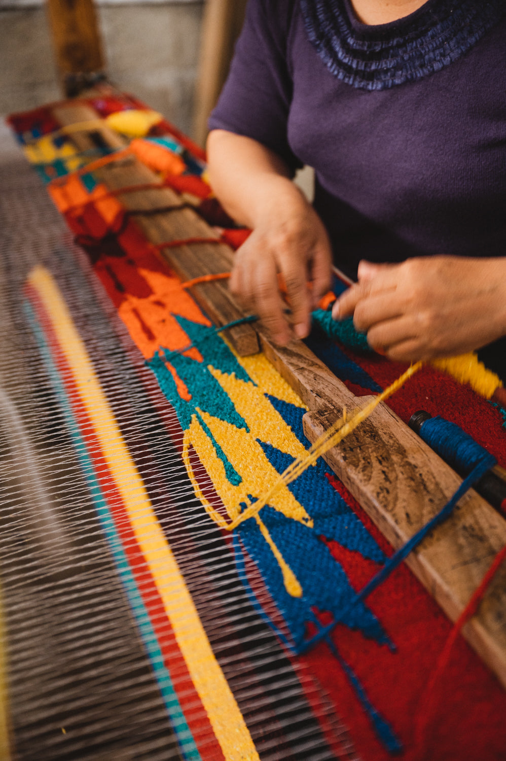 Woman hand weaving blanket on a wooden loom