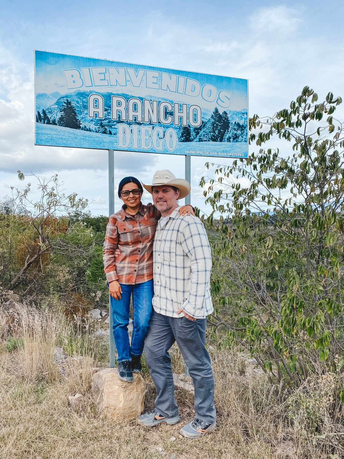 Owners of El Rancho Supply standing in front of hometown sign in Mexico