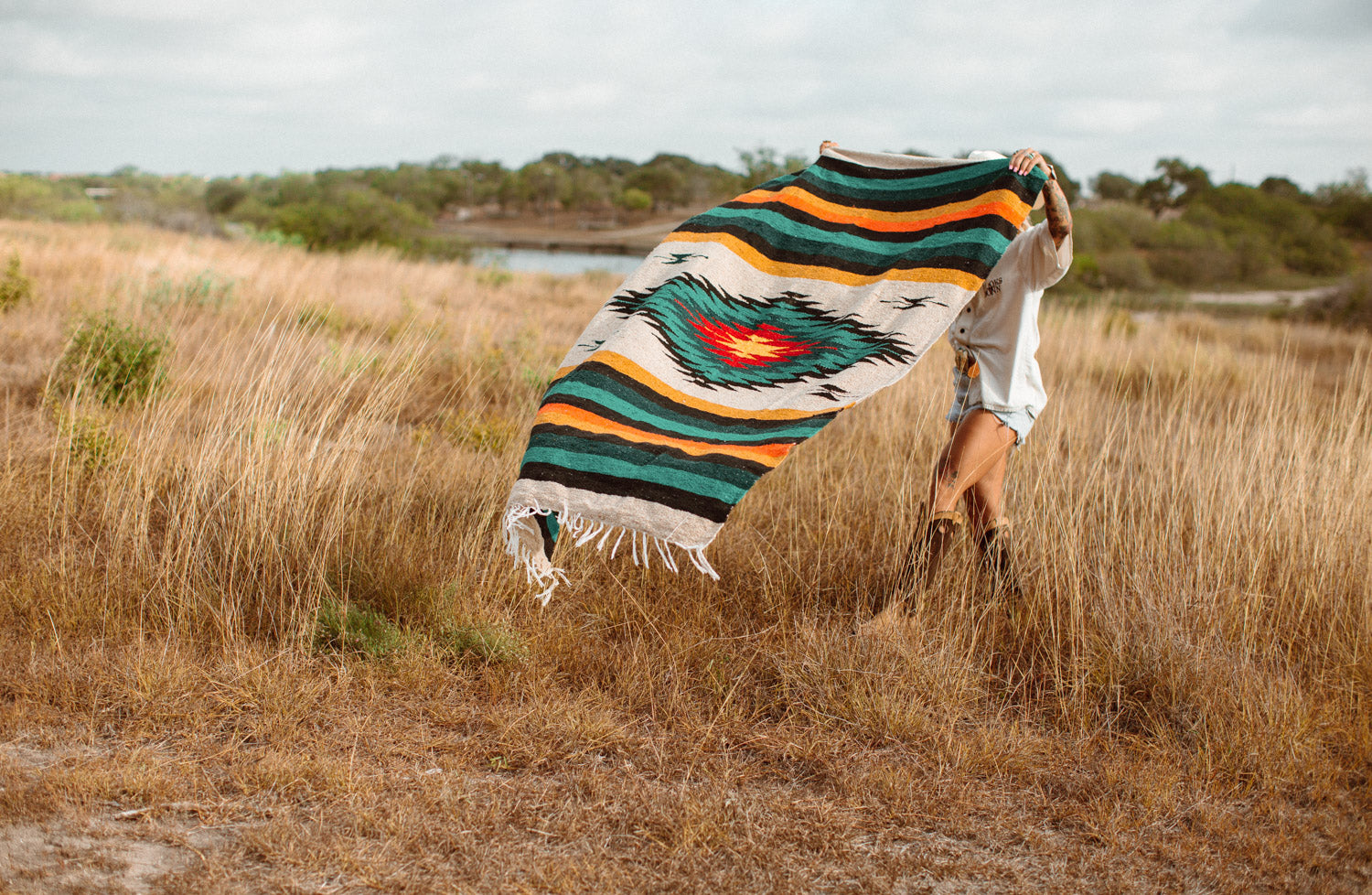 Girl spreading out diamond blanket in a field of tall dry grass