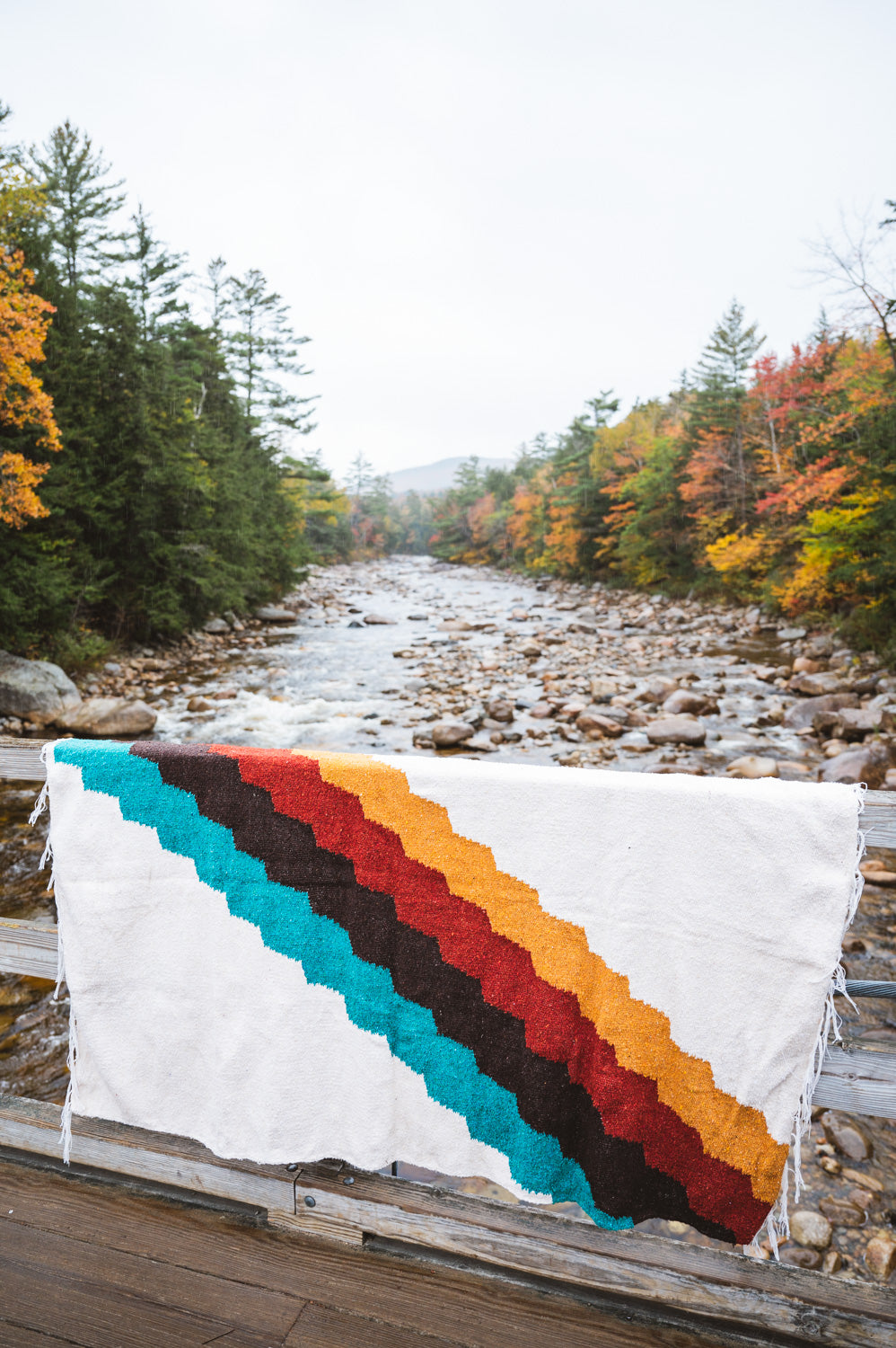 Colorful blanket hanging on side of bridge during autumn