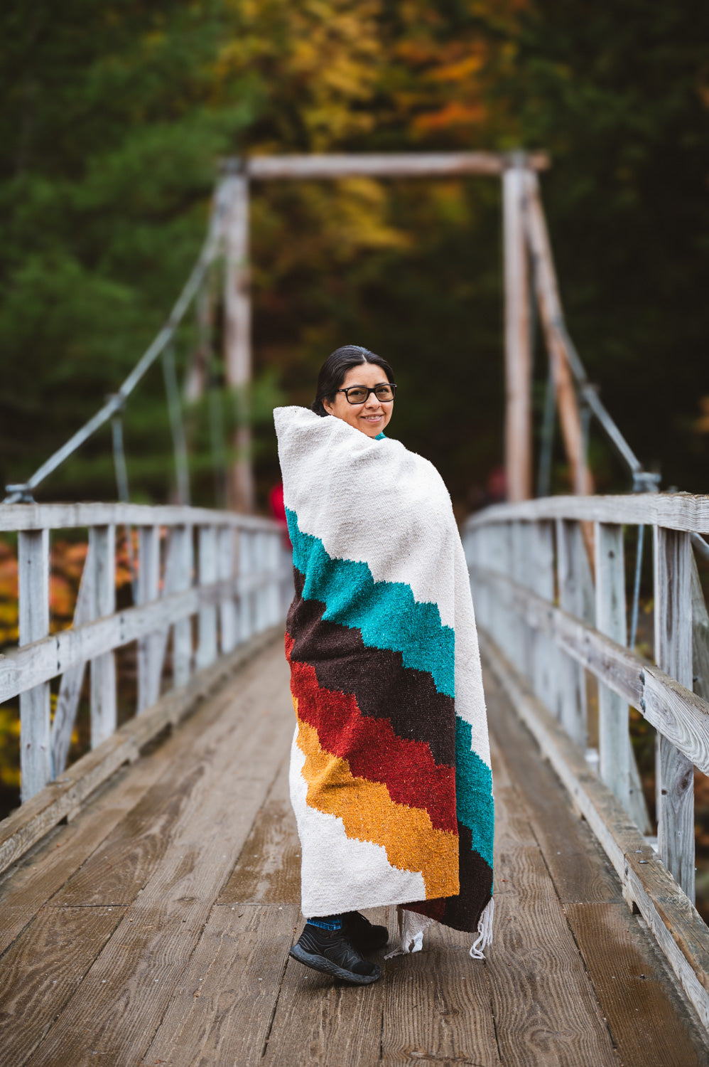 Girl standing on bridge wrapped in colorful blanket