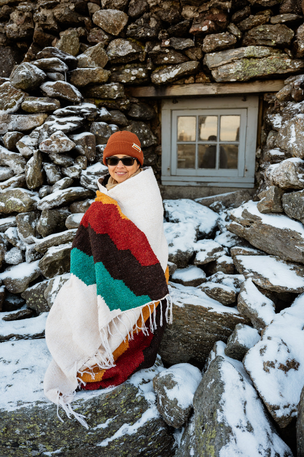 Girl wrapped in blanket in front of stone building during winter