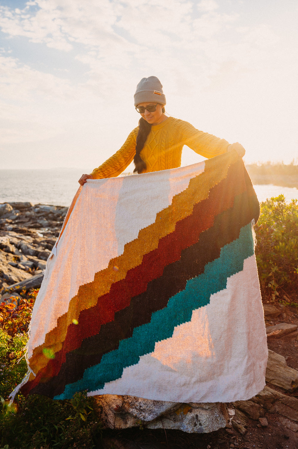 Girl holding colorful blanket at sunset