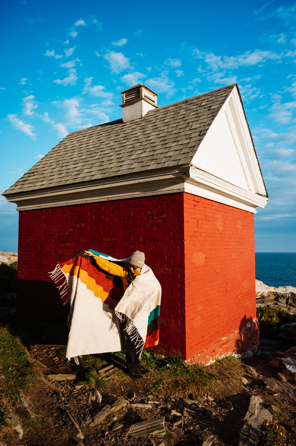 Girl wrapped in colorful blanket in front of red building