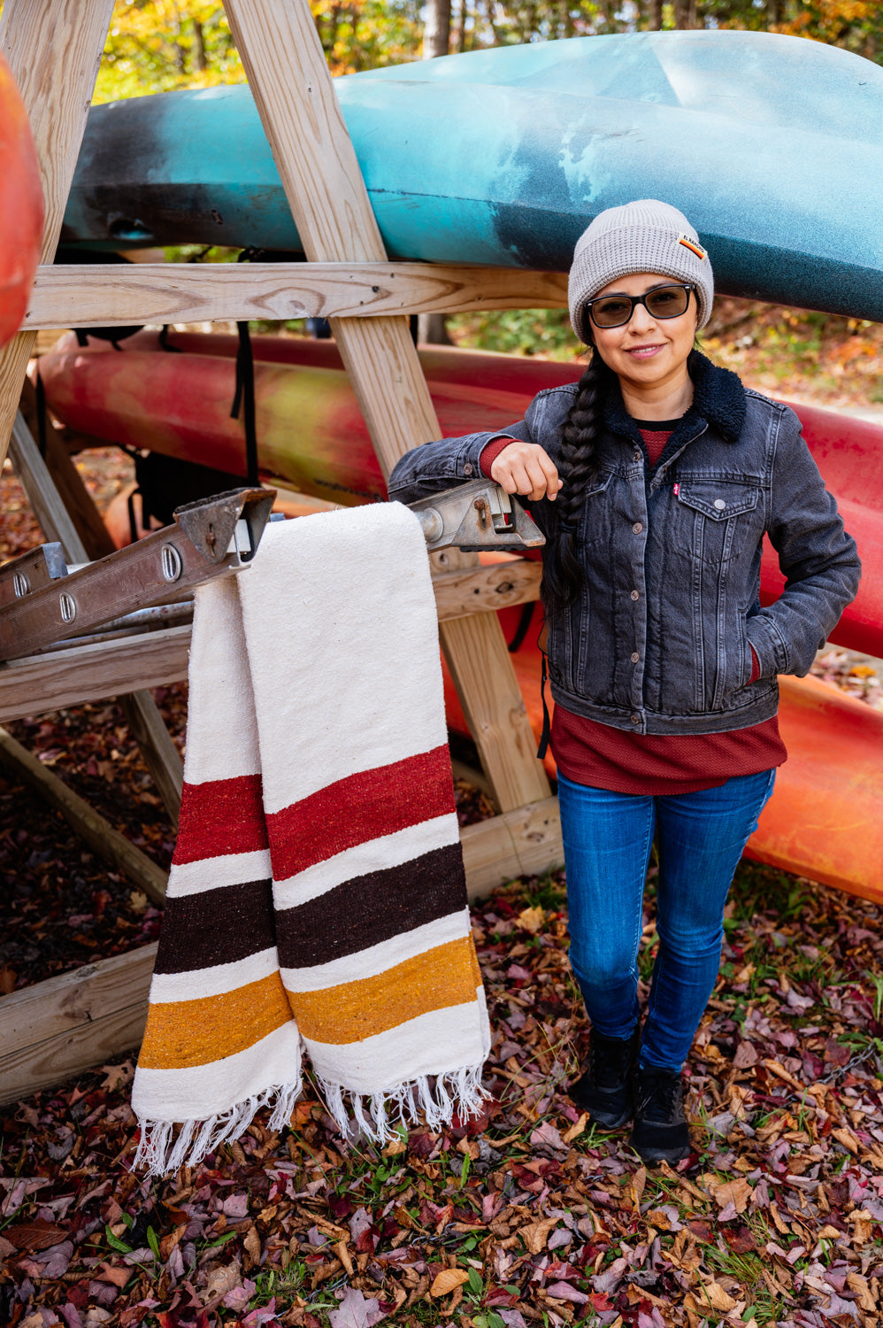 Girl standing in front of a canoe rack next to a striped blanket