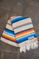 Multicolored Handwoven Saltillo Blanket laying on concrete floor folded in half