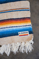 Multicolored Handwoven Saltillo Blanket laying on concrete floor folded in half