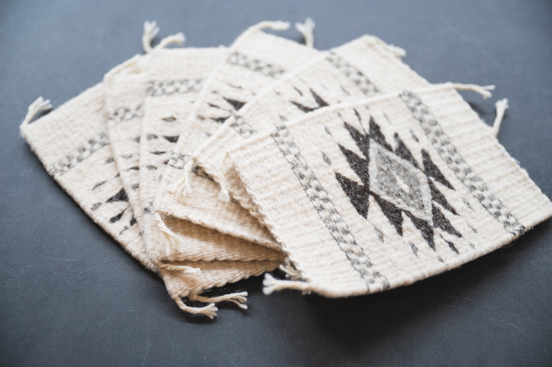 Neutral colored handwoven wool Zapotec coasters from Oaxaca on a black background