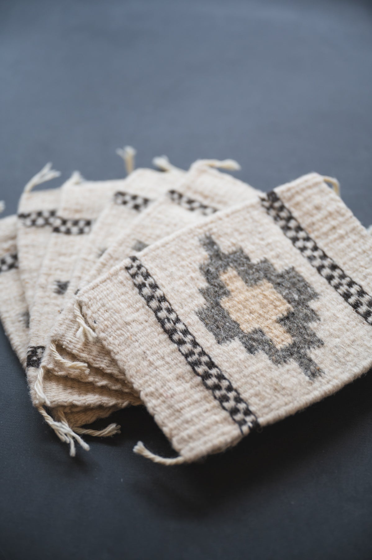 Neutral colored handwoven wool Zapotec coasters from Oaxaca on a black background