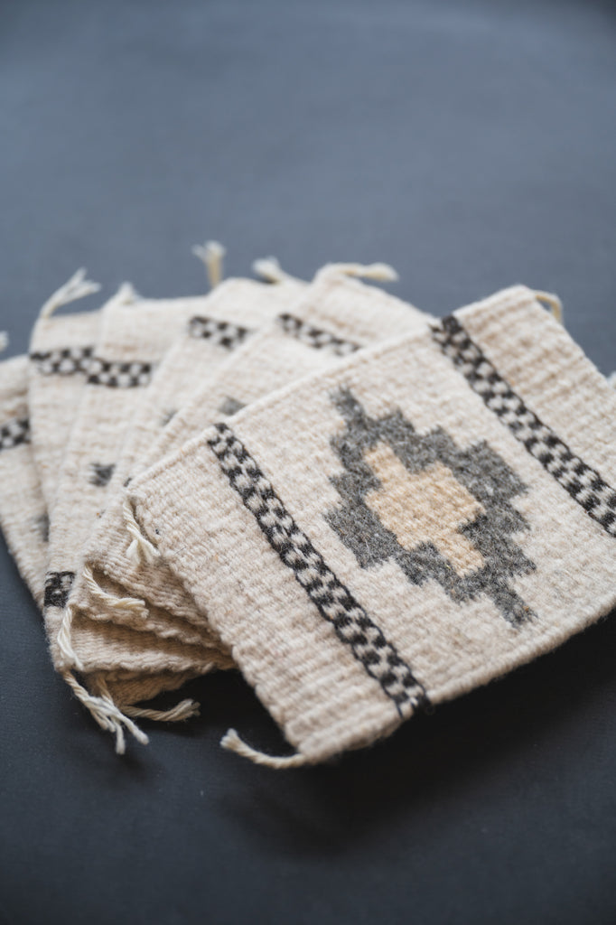 Neutral colored handwoven wool Zapotec coasters from Oaxaca on a black background