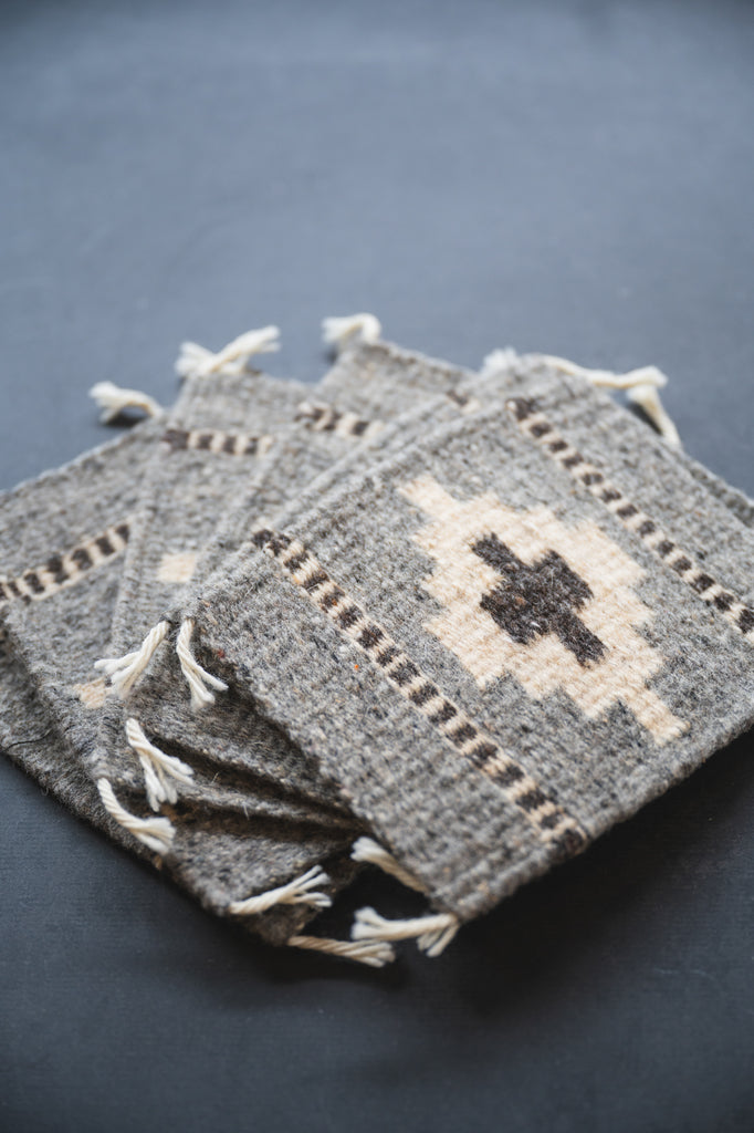 Neutral colored handwoven wool Zapotec coasters from Oaxaca on a black background