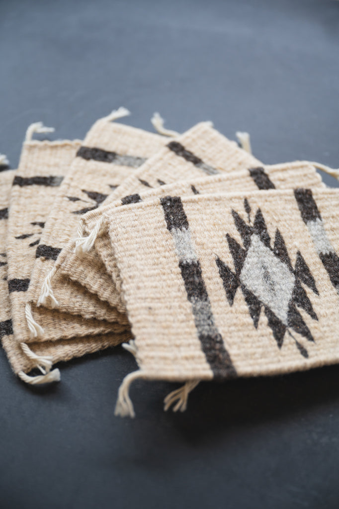 Neutral colored handwoven wool Zapotec coasters from Oaxaca on a black background