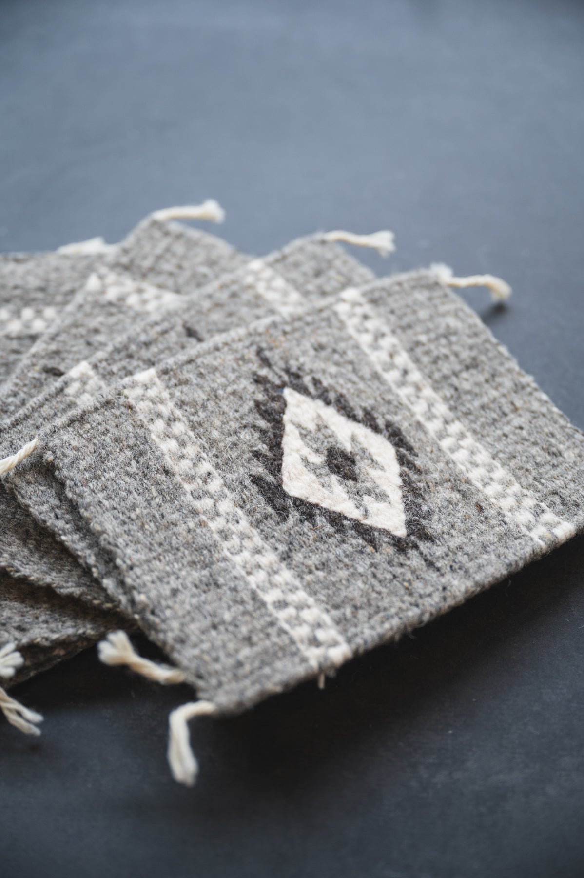 Neutral colored handwoven wool Zapotec coasters from Oaxaca on a black background