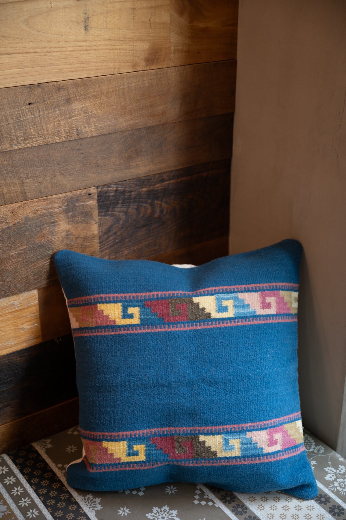 Navy blue colored Handwoven Zapotec pillow shawl sitting on a couch corner