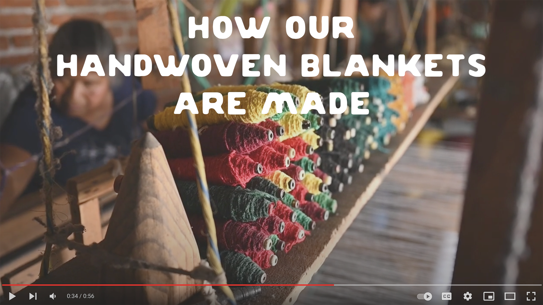 Screencap of handwoven blanket process youtube video showing yarn spools of various colors