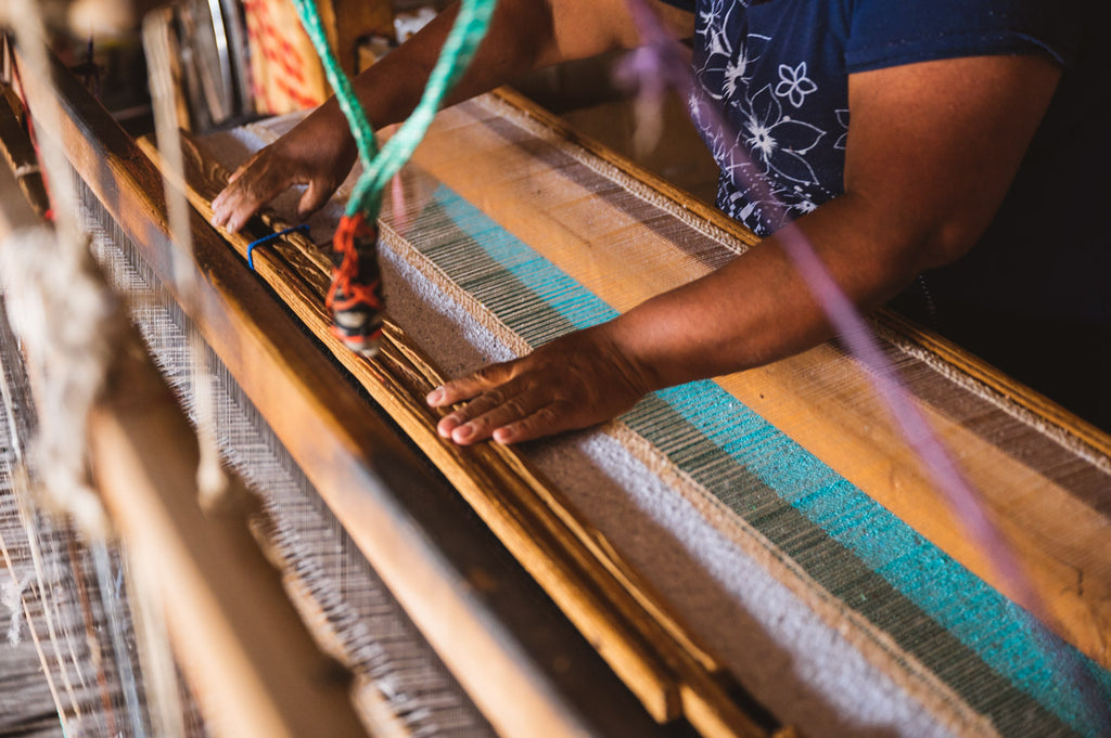 Woman hand weaving mexican blanket on wooden loom