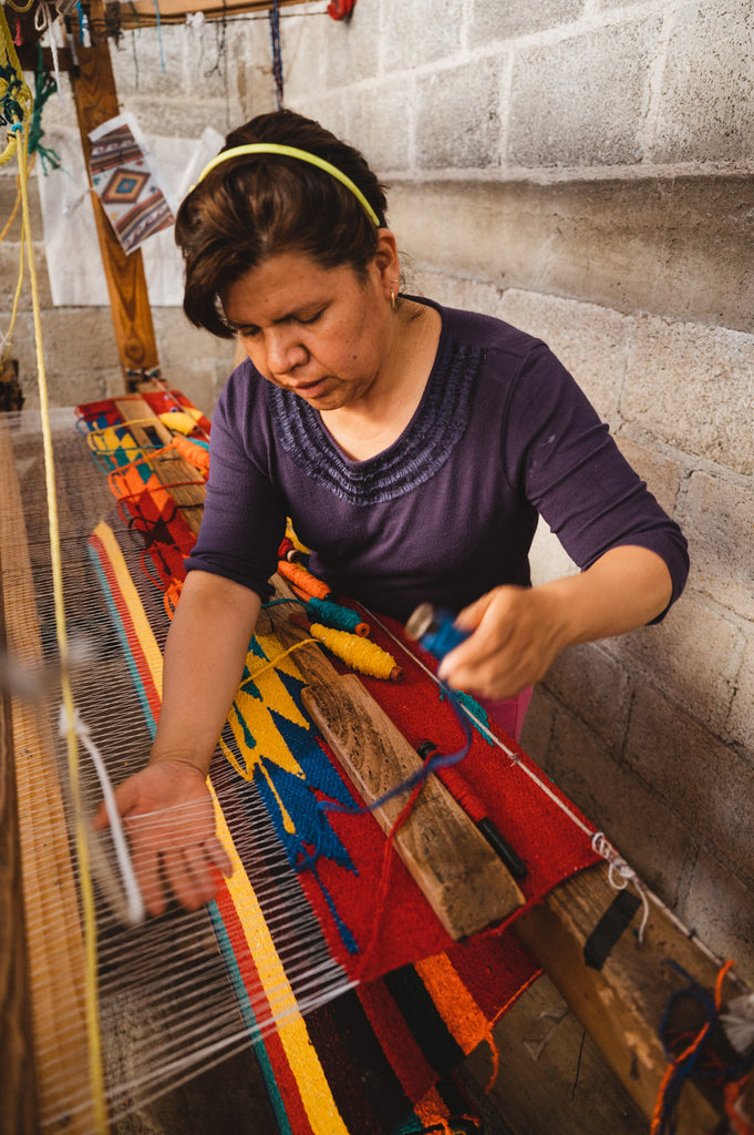 Woman hand weaving blanket on a wooden loom in Mexico