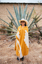 Girl wrapped in orange blanket in front of an agave in Oaxaca