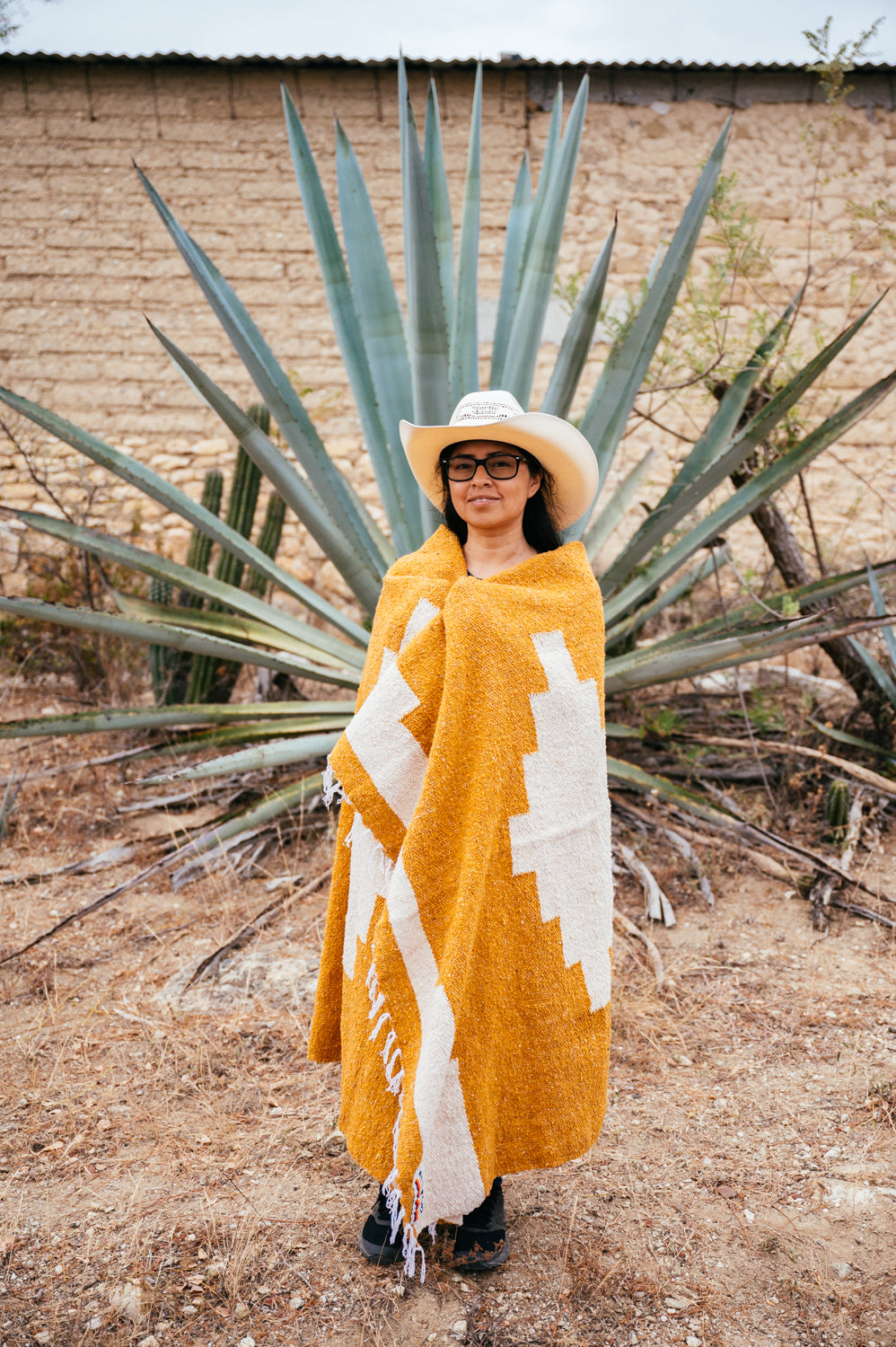 Girl wrapped in orange blanket in front of an agave in Oaxaca