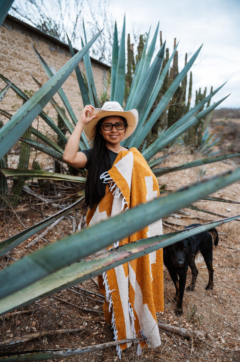 Girl wrapped in orange blanket in front of an agave in Oaxaca