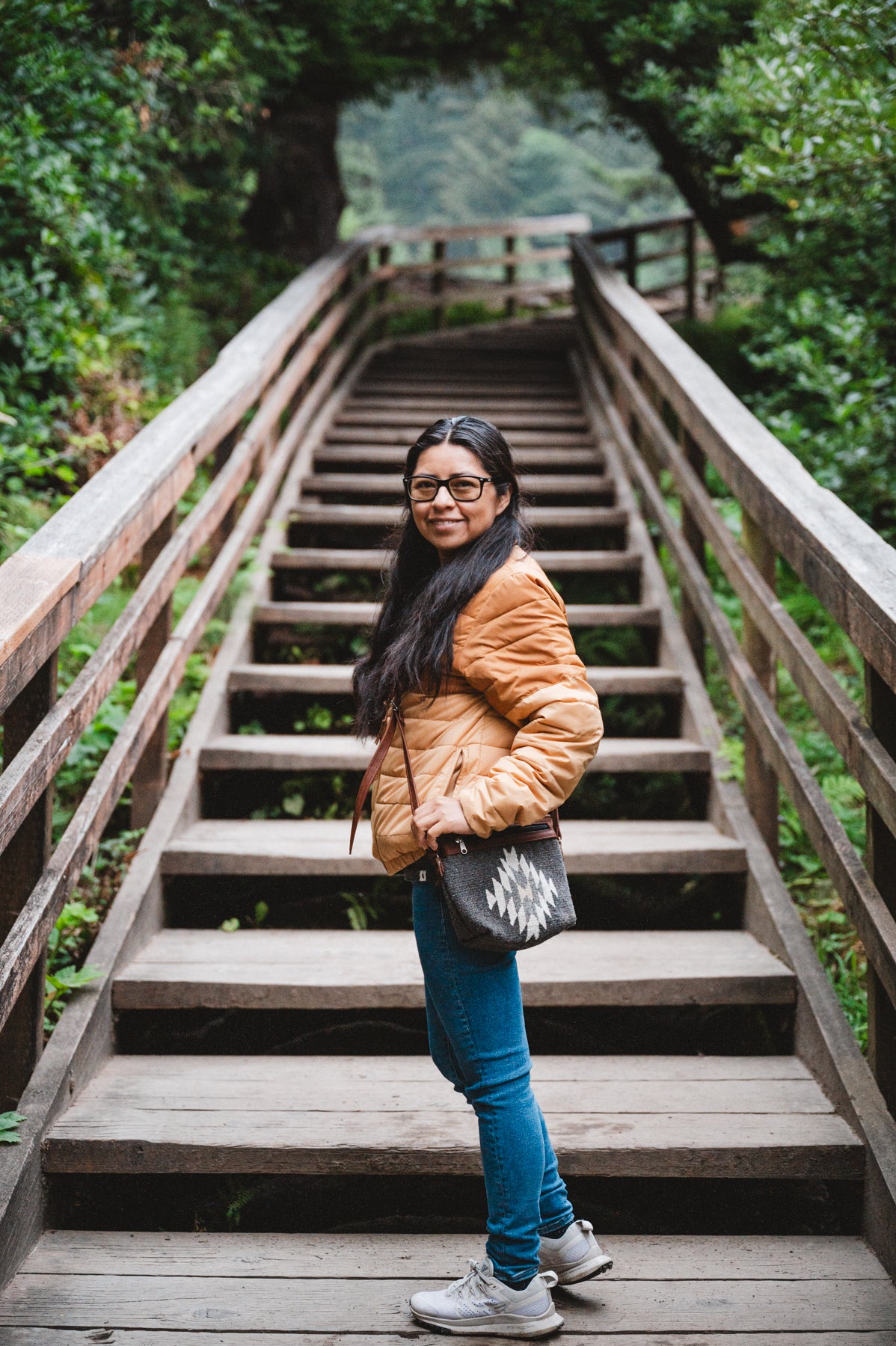 Charcoal colored handwoven wool purse being worn by girl in forest