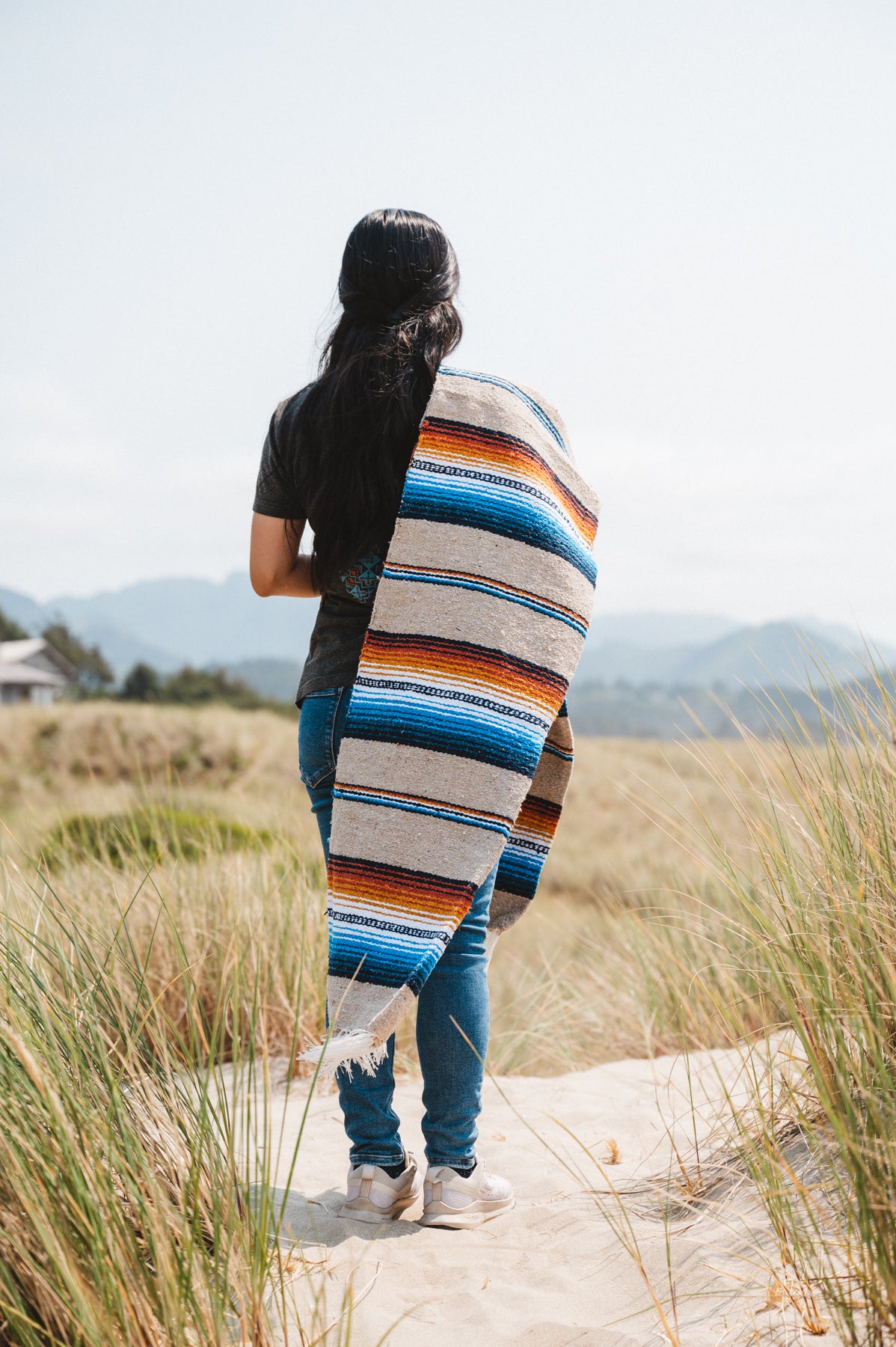 Girl wearing handwoven saltillo blanket in sand dunes