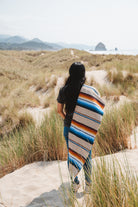 Girl wearing handwoven saltillo blanket in sand dunes