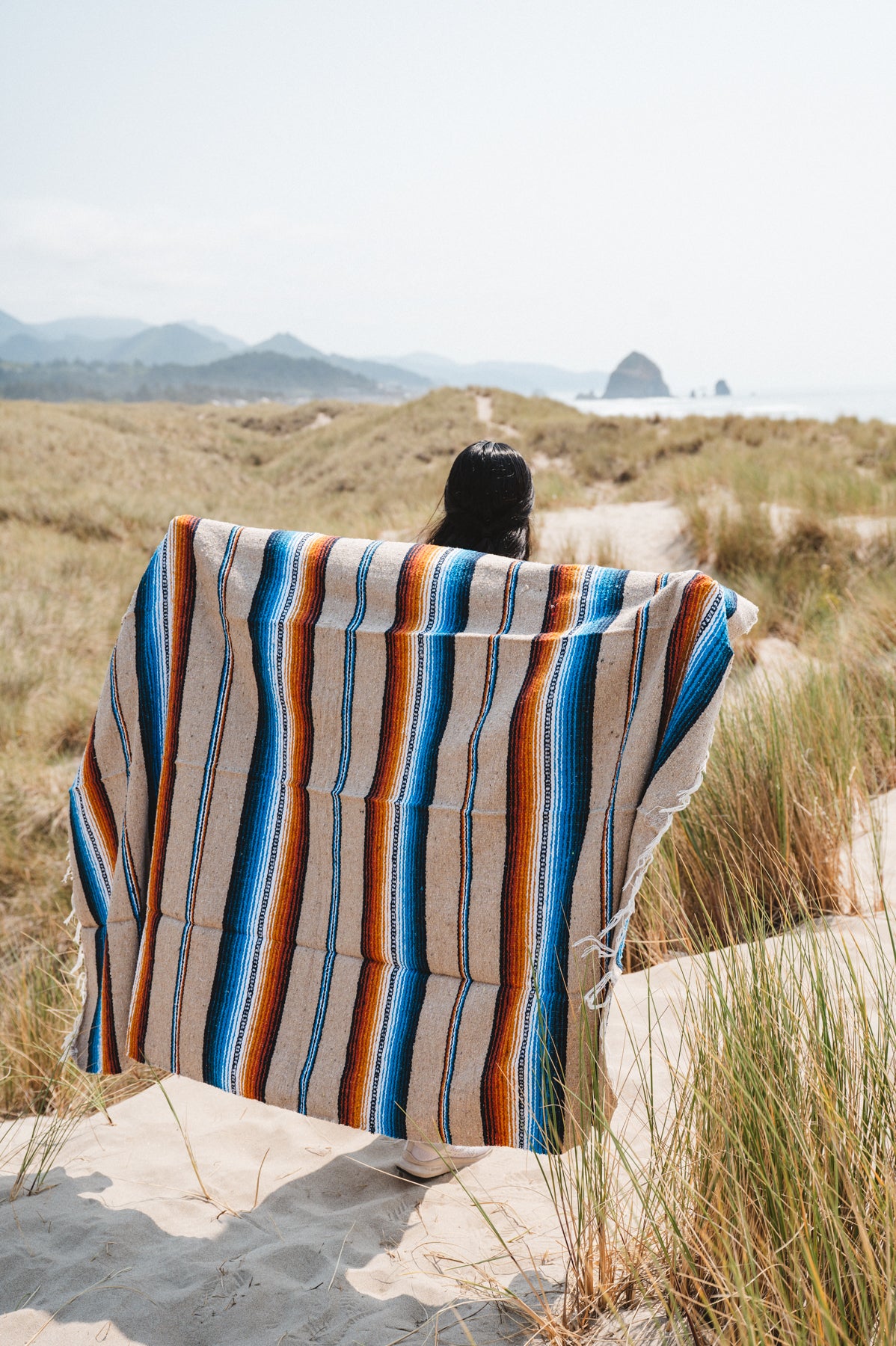 Girl wearing handwoven saltillo blanket in sand dunes