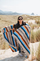 Girl wearing handwoven saltillo blanket in sand dunes