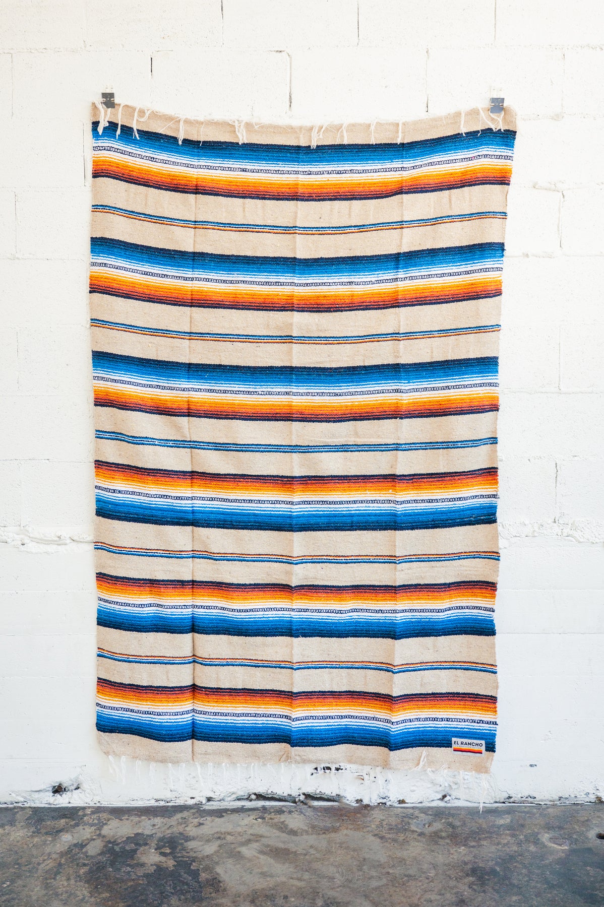 Saltillo blanket hanging from a white brick wall