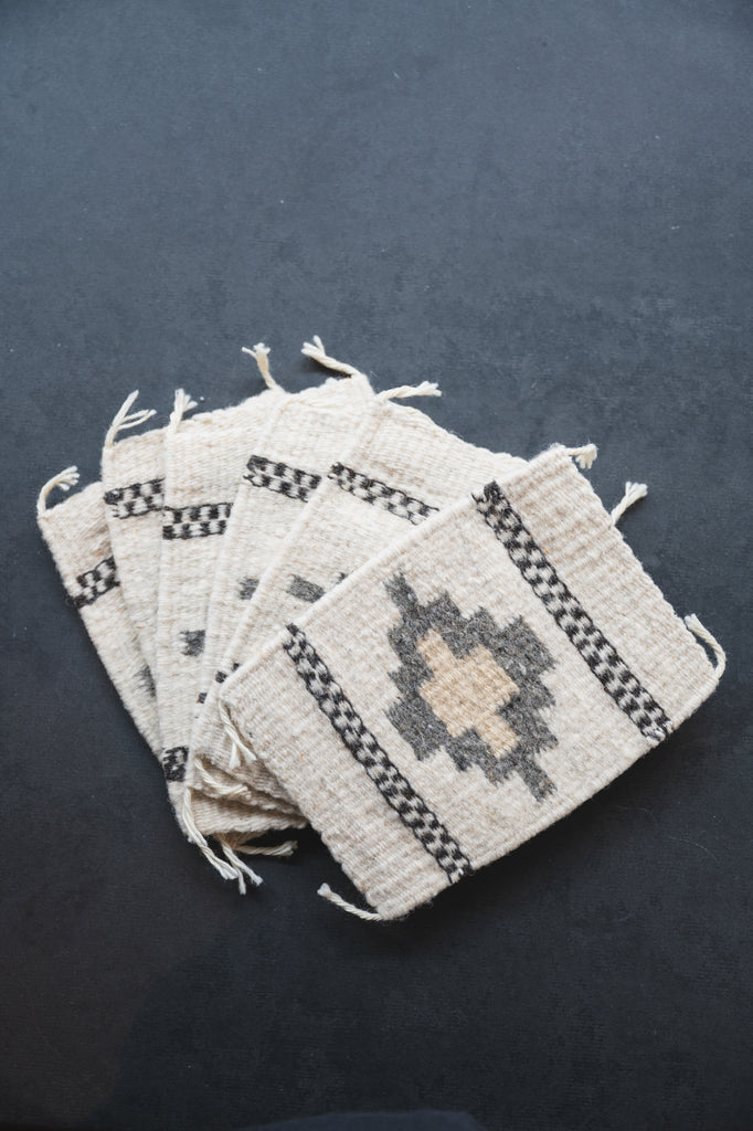 Neutral colored handwoven wool Zapotec coasters from Oaxaca on a black background