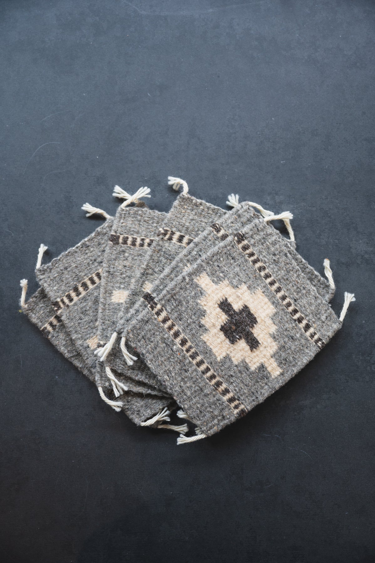 Neutral colored handwoven wool Zapotec coasters from Oaxaca on a black background