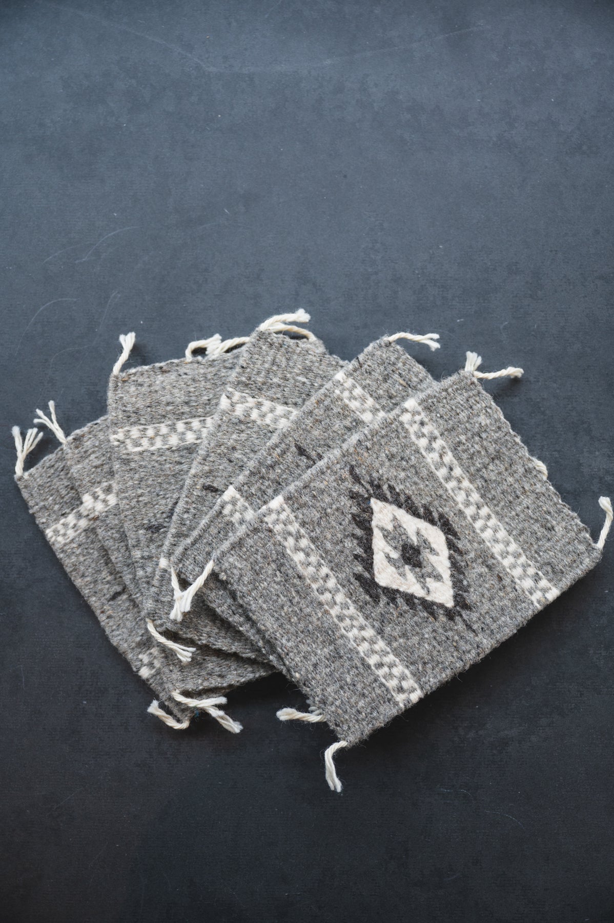 Neutral colored handwoven wool Zapotec coasters from Oaxaca on a black background