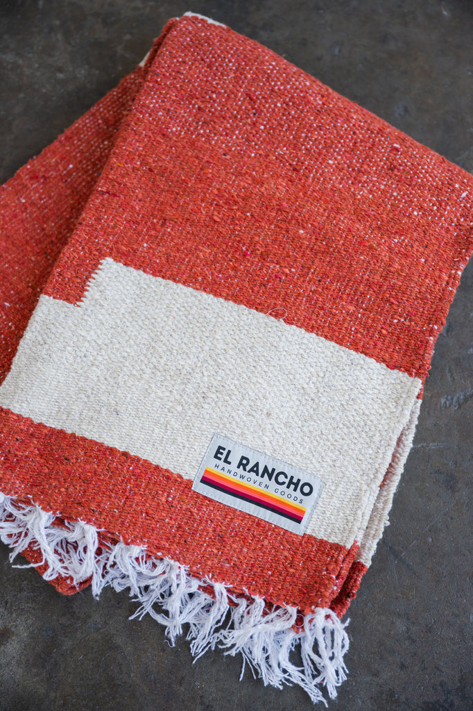 Red handwoven throw blanket folded laying on concrete floor
