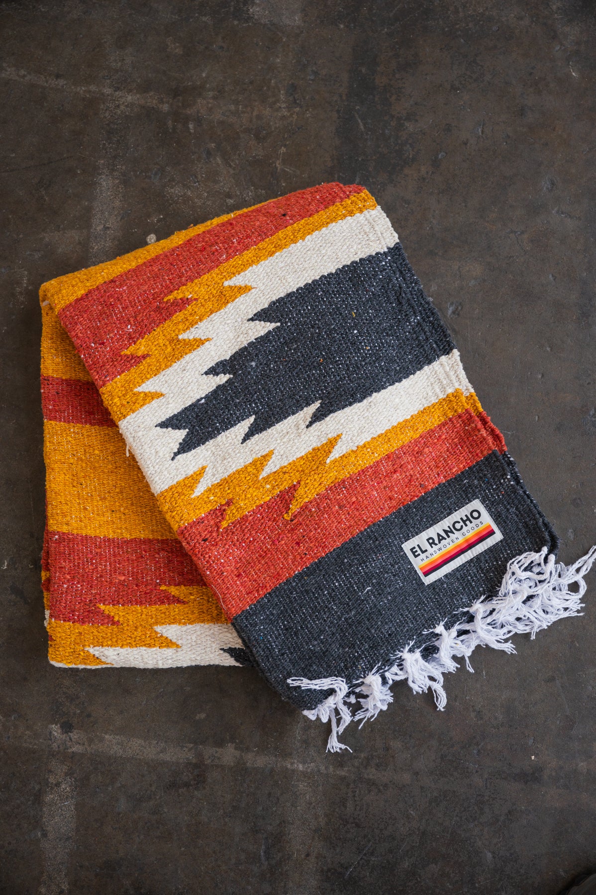 red and yellow mexican blanket laying on concrete floor