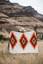 Woman holding up southwestern style diamond blanket in the high desert