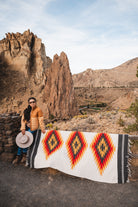 Woman standing next to southwester style diamond blanket laying over fence in the high desert