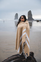 Woman wrapped in tan handwoven blanket in front of Haystack Rock Cannon Beach