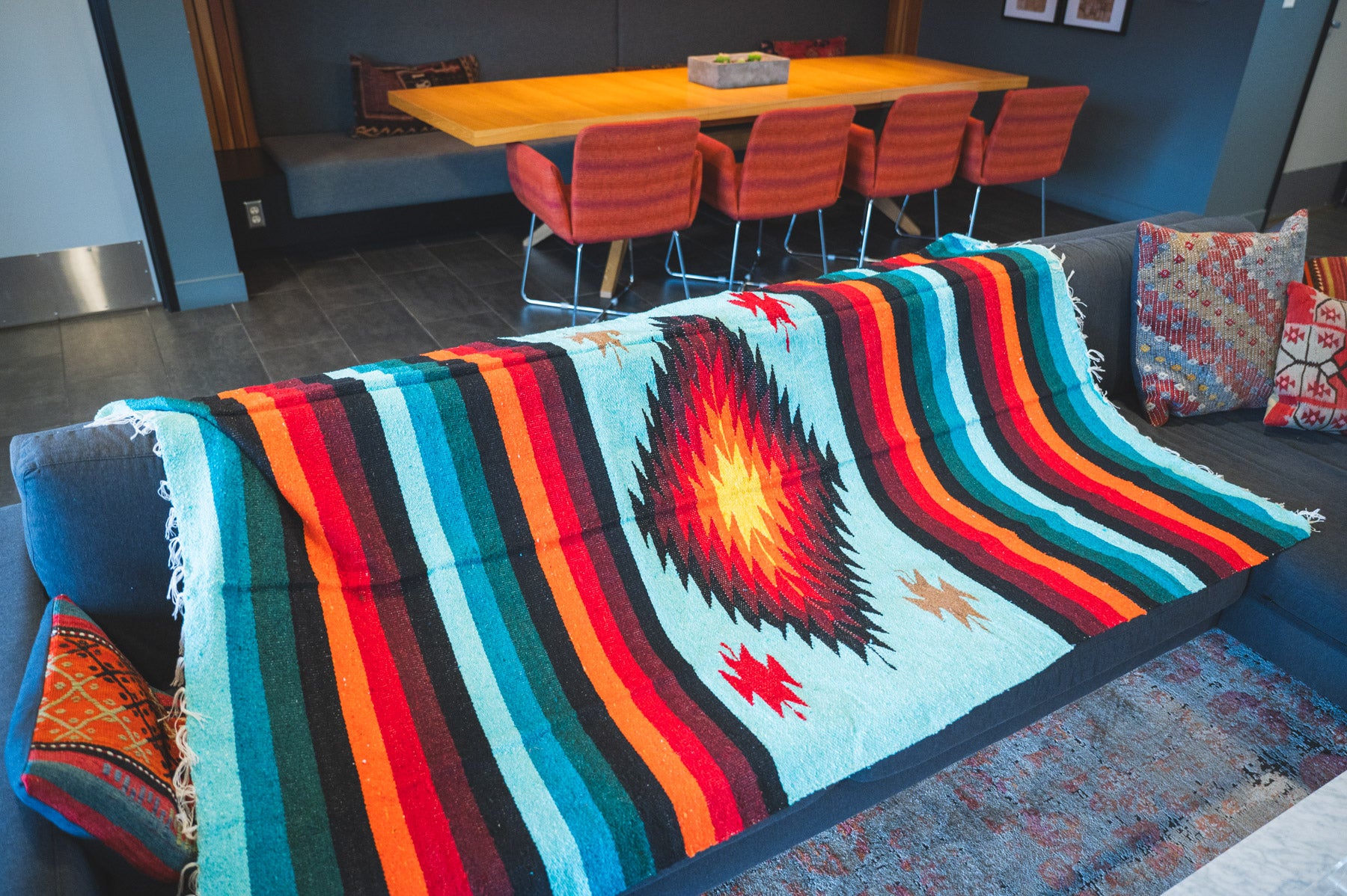 Teal and orange handwoven diamond zapatec blanket laying on a couch in a living room