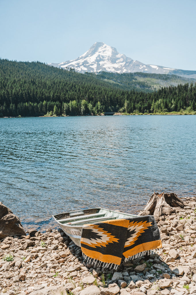 yellow and black zapotec relampago blanket laying on a boat in front of mountain lake