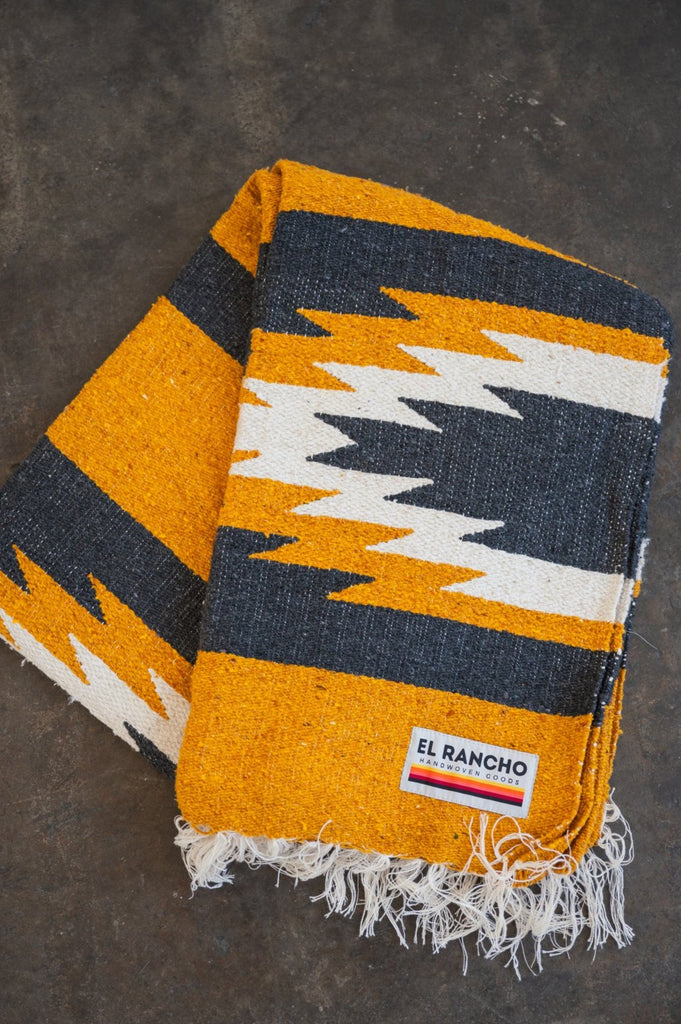 yellow and black relampago blanket laying folded on concrete floor