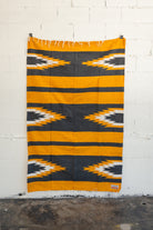 yellow and black relampago blanket hanging from white brick wall