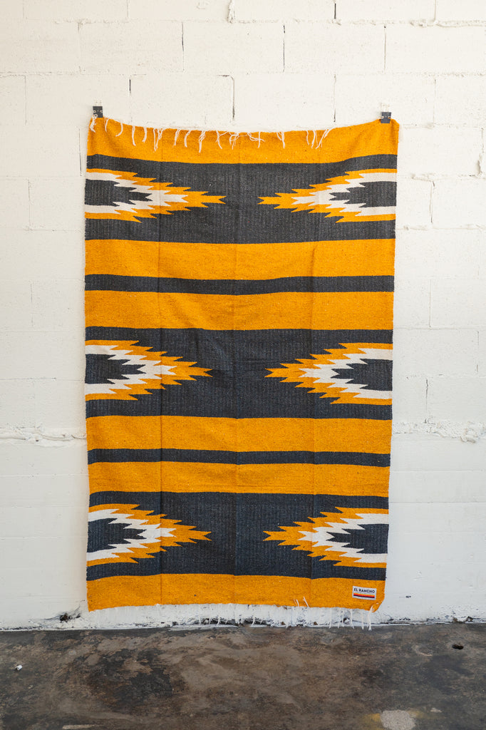 yellow and black relampago blanket hanging from white brick wall