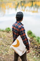 man holding a folded blanket in front of a lake