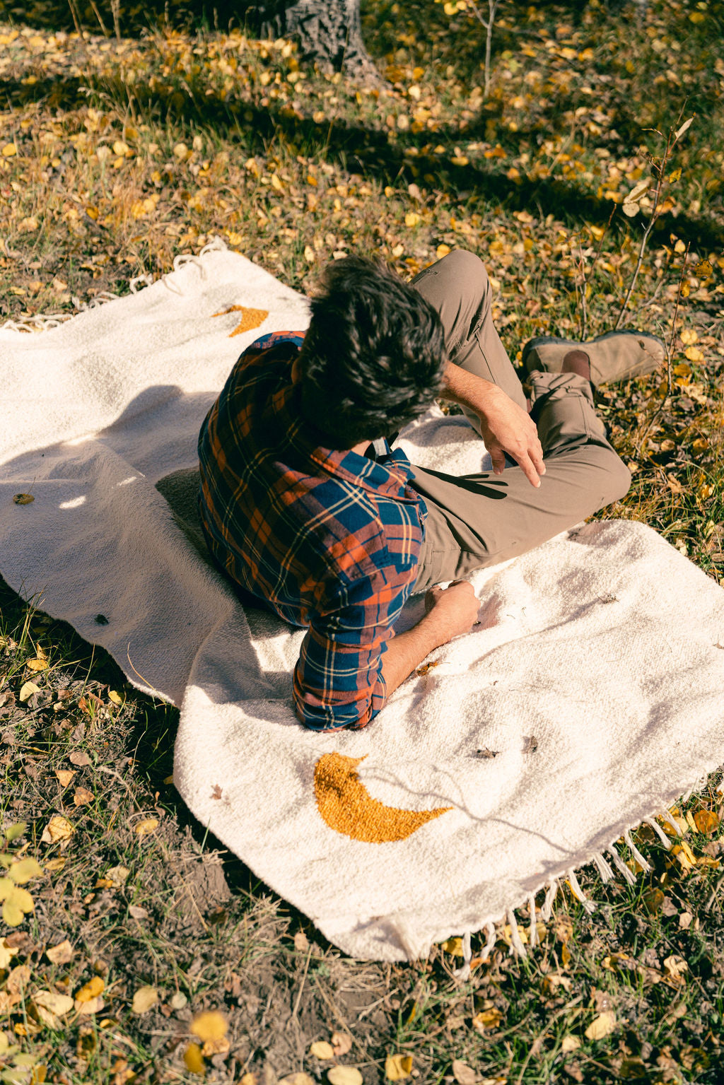 man sitting on cream blanket in the grass