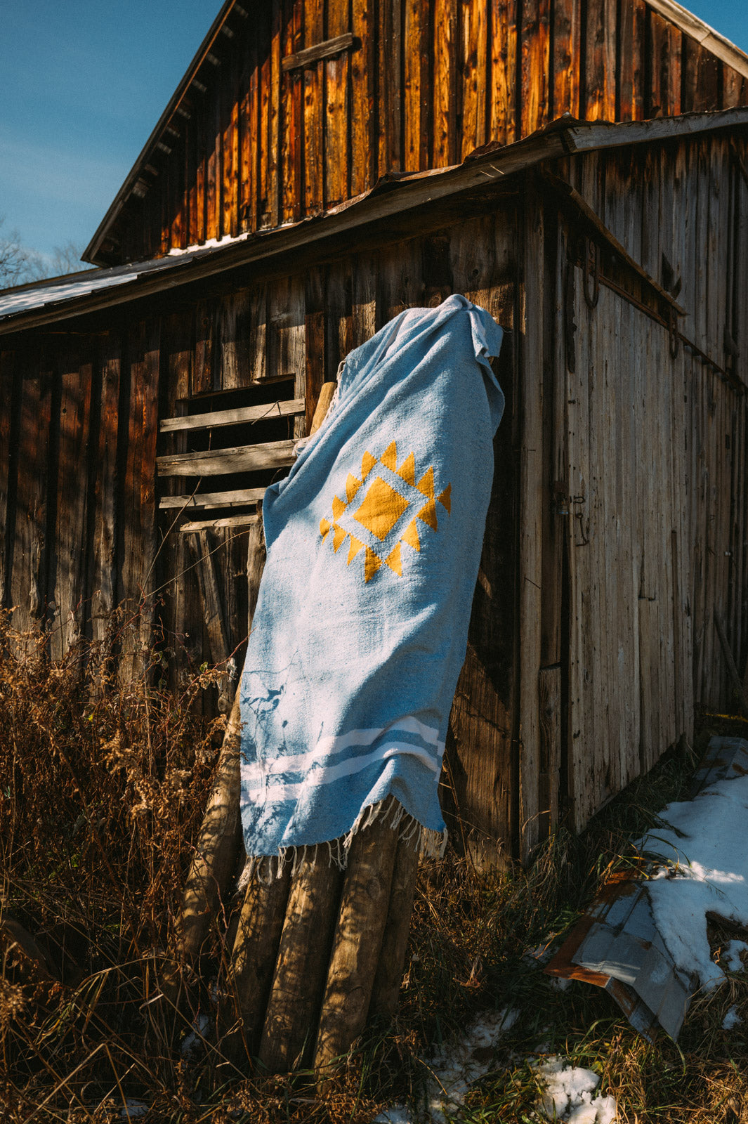 blue mexican blanket hanging from a barn